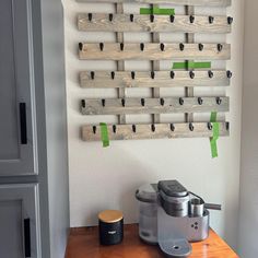 a coffee maker sitting on top of a wooden table next to a wall mounted coat rack