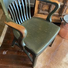 an old green chair sitting on top of a wooden floor