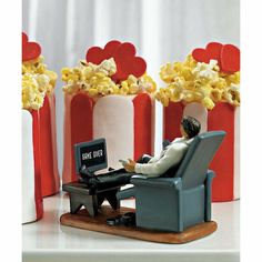 a toy man sitting in a recliner next to popcorn boxes and a laptop computer