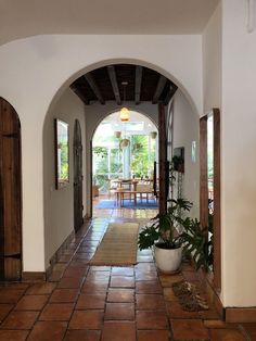 an archway leading to a dining room and kitchen area with potted plants on the floor