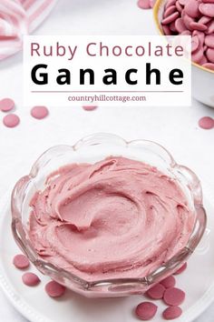 a bowl filled with chocolate ganache on top of a white plate next to pink candies