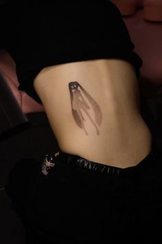 a woman's stomach with a small bird tattoo on the side of her belly