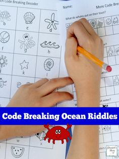 a child's hand holding a pencil and writing on an ocean riddles game