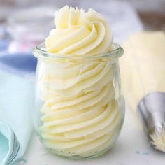 a glass jar filled with whipped cream next to a spoon and fork on a table