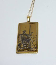 a gold necklace with an image of a man on horseback and the words queen & swords