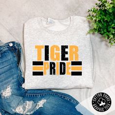 Our brand new school spirit sweatshirt Show your school spirit with this ash crewneck sweatshirt! Accented with a yellow and black design, this unique garment is sure to turn heads and have your friends shouting 'Go Tigers!' Features: multi color design on ash crewneck sweatshirt design is DTG pressed unisex fit runs true to size Brand: Gildan ﻿Use code: PICKUP at checkout for local pickup Pre-shrunk Crew Neck Sweatshirt For School Spirit, School Spirit Crew T-shirt For Streetwear, Cotton School Spirit Sweatshirt With Screen Print, Cotton Sweatshirt With School Spirit Screen Print, Gray Graphic Print Sweatshirt For Game Day, Gray Varsity Sweatshirt With Graphic Print, Black School Spirit Sweatshirt With Letter Print, College Style Game Day Sweatshirt With Graphic Print, College Style Sweatshirt With Graphic Print For Game Day