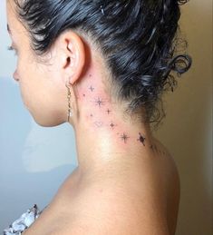 the back of a woman's neck with small stars on her left side and behind her ear