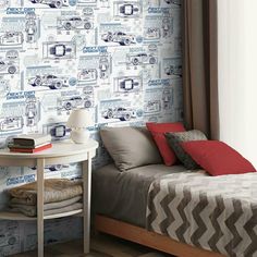 a bedroom with a bed, desk and wallpaper that has cars on the wall