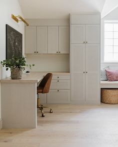 a room with white cupboards and a desk in the corner, next to a window