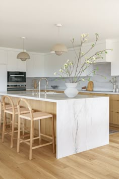 a large kitchen island with stools next to it and a vase filled with flowers