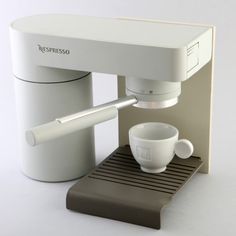 a white coffee machine with a cup on the side