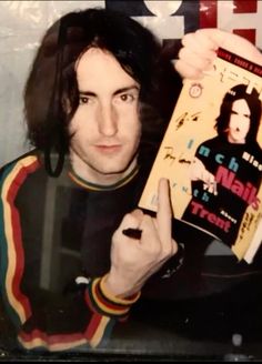 a man holding up a book in front of his face and pointing to the camera