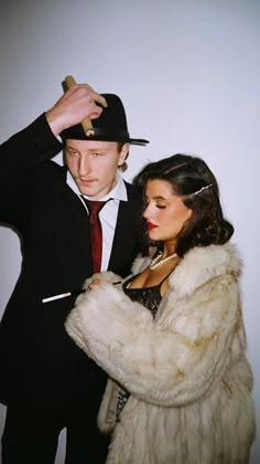 a man in a suit and tie standing next to a woman wearing a fur coat