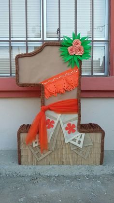 a piece of art made to look like a chair with an orange sash and flowers on it