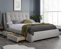 a bed that has drawers underneath it in a room with blue walls and hardwood floors