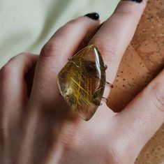 Make a statement and give the gift of clarity with our Rutilated Quartz Ring. This exquisite piece showcases the unique beauty of rutilated quartz, known for its delicate golden needles and powerful energy. It's more than a statement piece; it's a meaningful gift that captures the essence of insight and elegance. 🔸Adjustable band ring 🔸30 mm stone size 🔸Color may vary according to lighting 🔸Silver filled We offer  🔸Fast shipping  🔸Free shipping for eligible orders  🔸Polishing cloth  🔸Fre Unique Clear Crystal Ring As A Gift, Unique Clear Crystal Ring For Gift, Quartz Crystal Ring With Gemstone For Gift, Quartz Crystal Ring As A Gift, Quartz Jewelry Ring Gift, Quartz Ring Jewelry For Gift, Gift Crystal Quartz Ring With Gemstone, Handmade Citrine Crystal Ring As Gift, Handmade Amber Crystal Ring For Gift