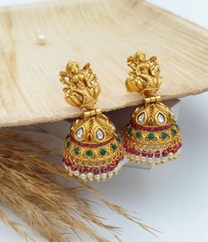 These exquisite Laxmi Jhumka Earrings embody the grandeur of South Indian temple jewelry. Crafted with intricate details, they feature the divine Goddess Laxmi motif, symbolizing wealth and prosperity. The classic dome-shaped jhumka design is adorned with traditional elements like antique gold plating, and delicate hanging beads for a touch of elegance and authenticity. Perfect for adding a royal touch to any ethnic attire, these earrings are a timeless piece of craftsmanship. Care Instructions: Fusion Style Earrings For Diwali Puja, Fusion Style Chandbali Earrings For Puja, Festival Peacock Design Earrings For Puja, Festive Fusion Earrings For Puja, Fusion Chandbali Earrings For Puja, Fusion Style Earrings For Puja And Festivals, Heavy Multicolor Earrings For Puja, Peacock Design Earrings For Puja Festivals, Laxmi Earrings