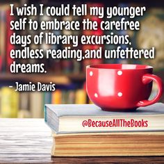 a red coffee cup sitting on top of a book next to a stack of books