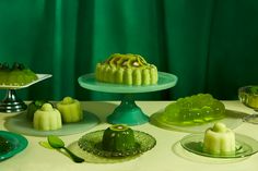 a table topped with cakes and desserts covered in green frosting