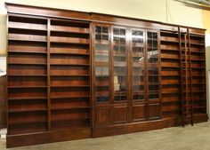 an empty room with wooden bookshelves and glass doors