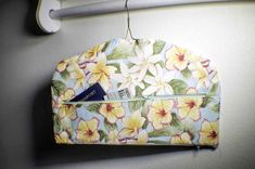 a purse hanging from a hook on a wall with yellow and white flowers in it