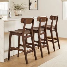 three wooden barstools sit in front of a white countertop and bar stools