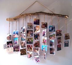 a group of photos hanging from a wooden stick on a wall with clothes pins attached to them