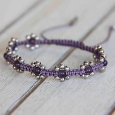 the beaded bracelet is made with silver beads and purple thread