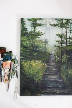 an oil painting of a path in the woods with brush and palettes next to it