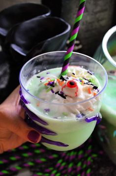 a hand holding a drink with sprinkles and candy on the rim, in front of other drinks