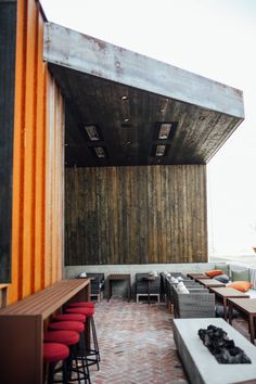 an outdoor seating area with tables, chairs and couches on brick patio next to large wooden structure