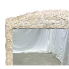 a large white stone mirror frame on the wall