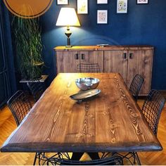 a wooden table with metal chairs and a bowl on it in front of a blue wall