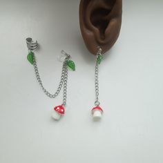 Made from silver tone charms, resin mushroom charms, with an ear cuff and metal free clip on finding, ear cuff and earring set make a unique addition to any outfit. The ear cuff is attached to an earring (your choice of clip on or pierced) with a chain. A green leaf and red and white mushroom hang from the attached earring. The single earring for the other ear is a coordinating design with leaf and mushroom, but without an attached ear cuff. The hinge back clip option uses classic hinge back sta Fairycore Mushroom, Red And White Mushroom, Ear Cuff Chain, White Mushroom, Ear Parts, Clip On Earring, Have Metal, Single Earring, Earring Findings