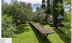 a wooden bench sitting in the middle of a lush green field next to an old building