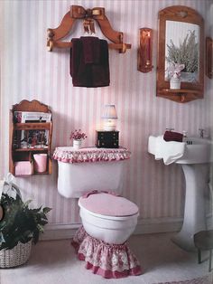 a pink and white bathroom with striped wallpaper, toilet, sink, mirror and potted plant