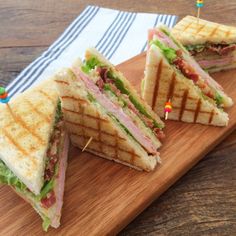 two sandwiches cut in half on a cutting board with toothpicks sticking out of them