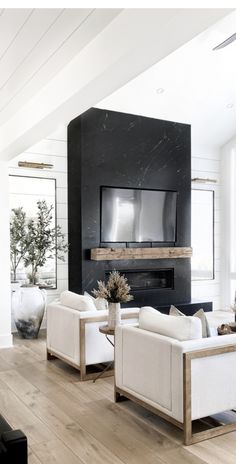 a living room filled with white furniture and a flat screen tv mounted on the wall