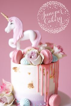 there is a cake decorated with pink and white icing, an unicorn on top