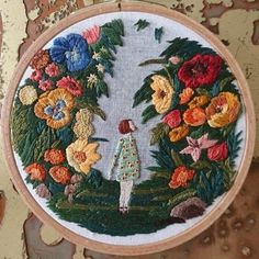 a woman is standing in the middle of flowers on a wall hanging ornament