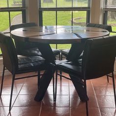 a dining table with four chairs in front of a large window overlooking a grassy field