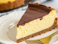 a piece of cheesecake on a white plate with a gold fork next to it