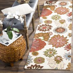 a white rug with flowers on it next to a wicker chair and planter