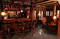 a bar with stools and chairs in front of an ornate display case filled with memorabilia