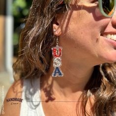 a woman wearing sunglasses and a pair of earrings with the letters usa hanging from it