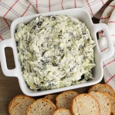 a white bowl filled with spinach dip surrounded by crackers