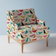 an upholstered chair with colorful birds and hearts on the back, against a blue background