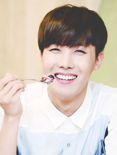 a young man is smiling and holding a spoon in his mouth