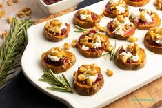 small appetizers are arranged on a white platter with rosemary sprigs