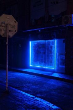 a purple light is shining on the side of a building in an alleyway at night